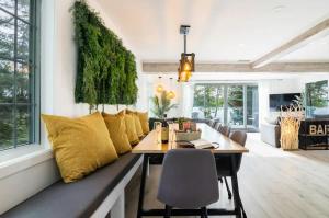 a dining room with a table and yellow pillows at L'Oasis Zen bord de L'eau & Spa in Nominingue
