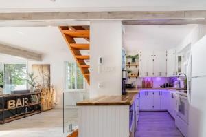 a kitchen with white cabinets and purple accents at L'Oasis Zen bord de L'eau & Spa in Nominingue