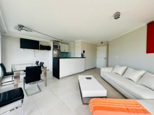 a living room with a white couch and a kitchen at Ocean drive 2 full amenities in Punta del Este