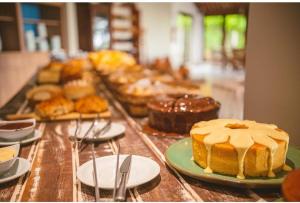 uma mesa coberta com bolos e outros produtos de pastelaria em pratos em Angá Beach Hotel em São Miguel dos Milagres