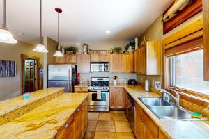 una cocina con armarios de madera y electrodomésticos de acero inoxidable en Cozy Mountain Retreat, en South Fork