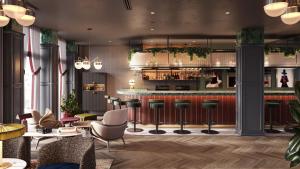 a lobby with a bar with stools and chairs at Radisson RED Berlin Kudamm in Berlin