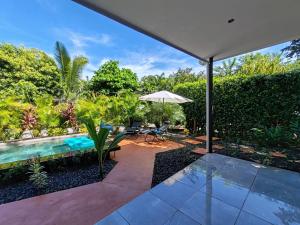 um pátio com uma piscina e um guarda-sol em Casa Adams - Apartamentos Adams em Tamarindo