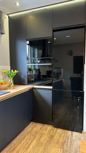 a kitchen with black cabinets and a wooden floor at Domki Lubiane in Brenna