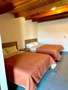 two beds in a hotel room with wooden ceilings at Hotel towi in Creel