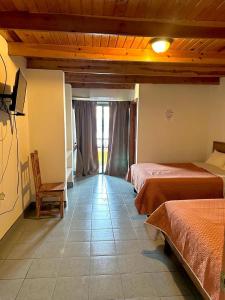 a room with two beds and a chair in it at Hotel towi in Creel