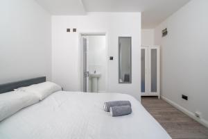 biała sypialnia z dużym białym łóżkiem z ręcznikiem w obiekcie Cozy Studio Flat- Dalston Central w Londynie
