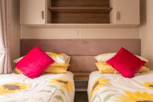 two beds with pink and yellow pillows in a room at 62 Meadow View in Ilfracombe
