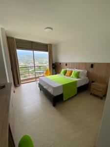 a bedroom with a large bed and a large window at Caliview Apartahotel in Cali