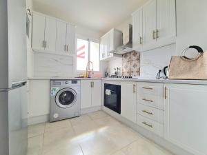 a kitchen with white cabinets and a washing machine at Superbe appartement avec une vue panoramique sur piscine in Cabo Negro