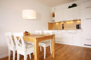 uma cozinha com uma mesa de madeira e armários brancos em Meer & Strand - Haus Meeresstrand Ferienwohnung 213 em Scharbeutz