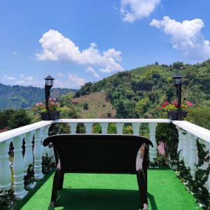 un banco sentado en un balcón con vistas en Ecohotel Java en Manizales