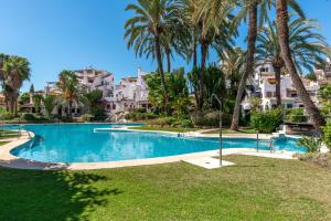 a swimming pool with palm trees and houses at Aldea Blanca Cozy Penthouse in Puerto Banús in Marbella
