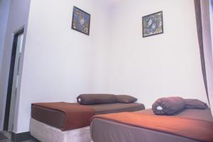 two beds in a room with two pictures on the wall at KAZAIN HOTEL in Yogyakarta