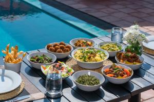 a table topped with bowls of food next to a pool at Ceylo Villas in Bentota
