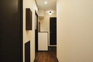 - un couloir avec des portes noires et blanches et du parquet dans l'établissement 大同：14時からお泊まり, à Osaka