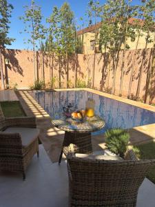 une terrasse avec une table, des chaises et une piscine dans l'établissement Villa djelloul, à Marrakech