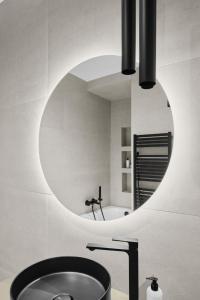 baño con espejo redondo y lavabo en Hotel Collect & Residence, en Budapest