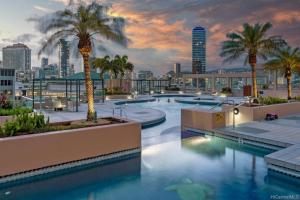 a hotel pool with palm trees and a city skyline at The Landmark #2705 in Honolulu