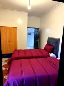 um quarto com 2 camas e lençóis vermelhos em le studio du lac em Lalla Takerkoust