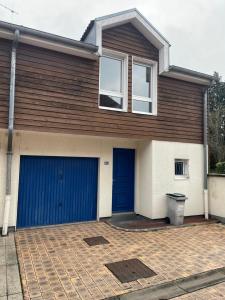 a house with blue garage doors on a brick driveway at Sérénité au cœur de ville in Saint-Dizier