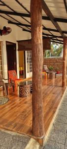 Un porche con suelo de madera y un árbol. en Jonirene Seasands, en Alleppey