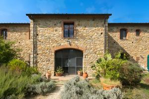 Agriturismo Fattoria di Statiano في بومارانسي: مبنى حجري مع نافذة كبيرة ونباتات