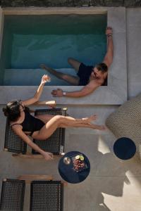 a man and woman sitting in a swimming pool at Alaso Design Suites in Fira