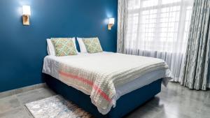 1 dormitorio azul con 1 cama con pared azul en The Fairway Residence en Nyeri
