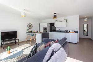 uma sala de estar com um sofá azul e uma cozinha em L17 Arenas Suite 3 balconies 5mins to the Sea em Nice