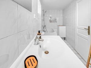 een witte badkamer met een wastafel en een bad bij L'Écrin de Noiseau in Noiseau