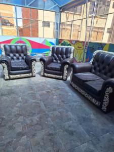 three chairs and a couch in front of a mural at Backpacker Oruro in Oruro