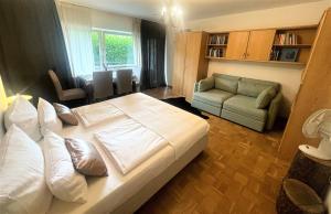 1 dormitorio con 1 cama blanca grande y 1 sofá en Gemütliches Apartment My Little Black Forest en Friburgo de Brisgovia