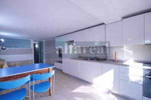 una cucina con armadi bianchi e sedie blu di appartamento MONO GLICINE ristrutturato, veranda e clima a Castiglione della Pescaia
