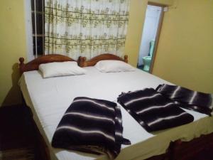 Una cama con dos toallas blancas y negras. en ohiya colonial bungalow, en Ohiya
