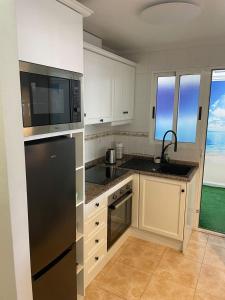 a kitchen with white cabinets and a black refrigerator at Parque De Las Naciones Europa II in Torrevieja