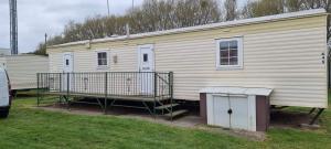 a large white mobile home with a porch and stairs at promenade direct beach access in Ingoldmells