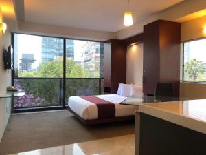um quarto de hotel com uma cama e uma grande janela em Suites Capri Reforma Ángel 380 em Cidade do México