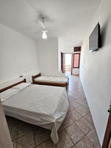 a bedroom with two beds and a flat screen tv at Pousada Varanda da Praia in Conceição da Barra