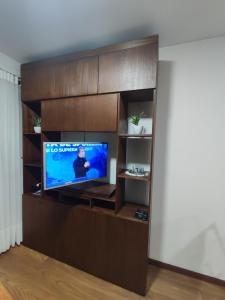 a living room with a tv in a wooden entertainment center at Excelente ubicación y cómoda estadía in La Paz