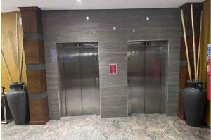 Dos ascensores plateados en un edificio con jarrones en Wynn Apt - Luxe / Uninterrupted Power / Near Mall / Sleeps 3, en Kumasi