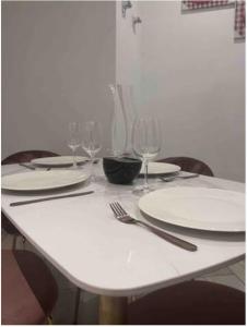 a table with white plates and wine glasses on it at Wynn Apt - Luxe / Uninterrupted Power / Near Mall / Sleeps 3 in Kumasi