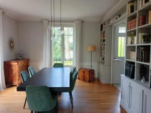 a dining room with a black table and green chairs at Maison familiale tout confort in Chatou