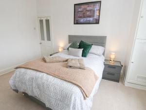 een slaapkamer met een groot bed met groene kussens bij Luna Cottage in Holmfirth