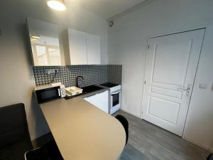 une cuisine avec une table, un évier et une porte dans l'établissement La Recouvrance-centre ville-wifi, à Niort