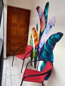 two red chairs and a plant next to a door at Gloria’s Cozy Apartment in La Romana