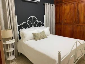 a bedroom with a white bed with white pillows at Gloria’s Cozy Apartment in La Romana