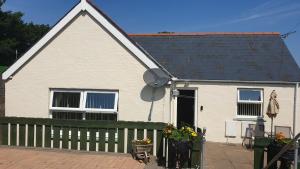 a white house with a black roof and a fence at Cosy Pembrokeshire Home in Pembrokeshire