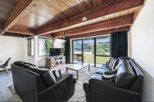 Sala de estar con 2 sofás de cuero y TV en Rakaia Gorge Views - Mt Hutt, en Windwhistle