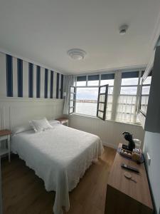 1 dormitorio con cama, mesa y ventanas en Hotel El Pescador en Tazones
